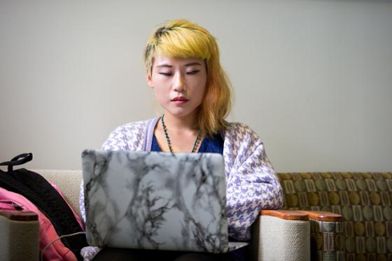 图为网上赌博平台的一名女学生正在用笔记本电脑工作