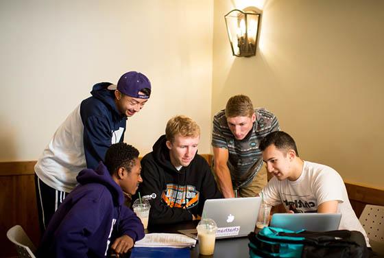 图为一群网上赌博平台的男学生围着几台笔记本电脑一起工作