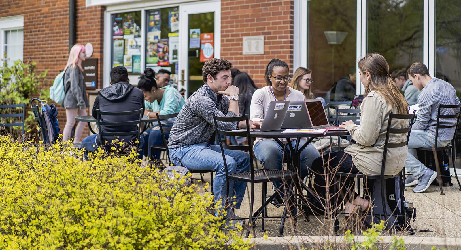 图为网上赌博平台的学生们在Shadyside校区的Cafe Rachel前的户外露台桌子上工作.
