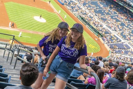  两名网上赌博平台唱诗班的女学生穿着相配的紫色t恤，在匹兹堡海盗队的比赛中合影.